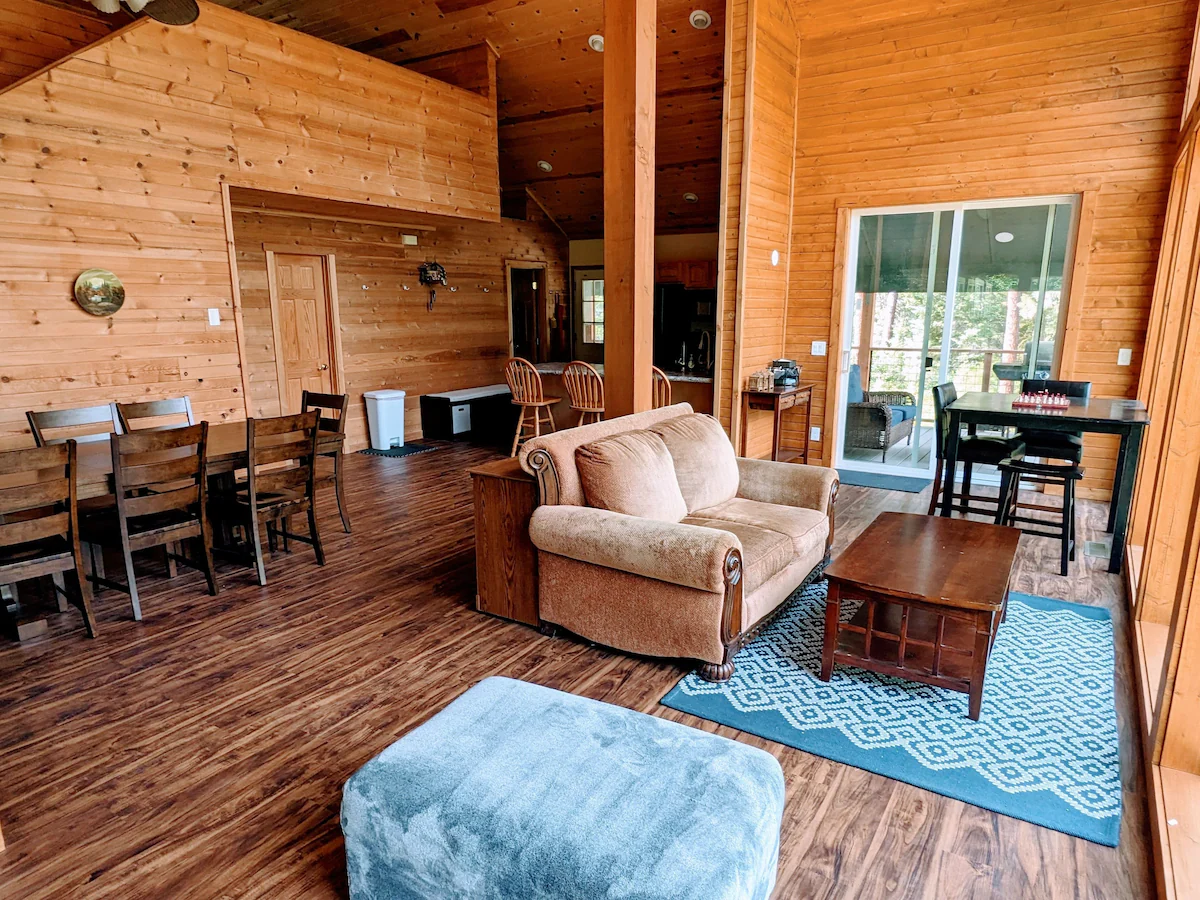 Crouch Cabin great room with sofa, dining table, and pine-paneled walls